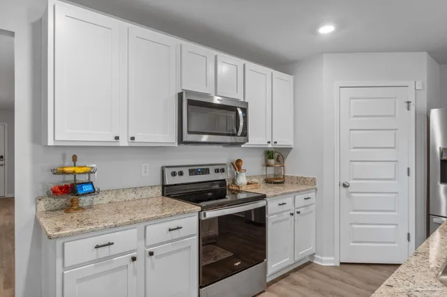 a kitchen with granite countertop white cabinets and stainless steel appliances