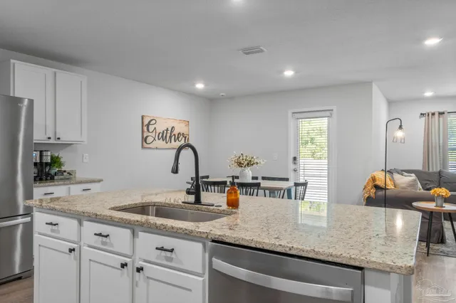 a kitchen with granite countertop a sink and white cabinets