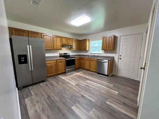 a kitchen with stainless steel appliances granite countertop a refrigerator a stove top oven a sink and dishwasher