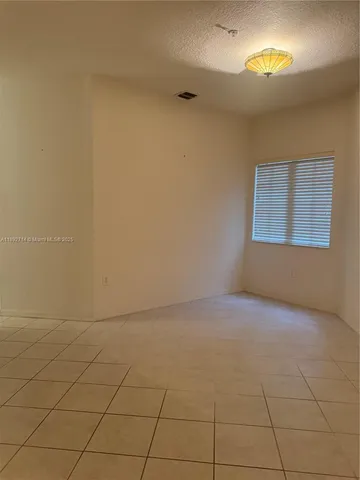 a view of an empty room with wooden floor and a chandelier fan