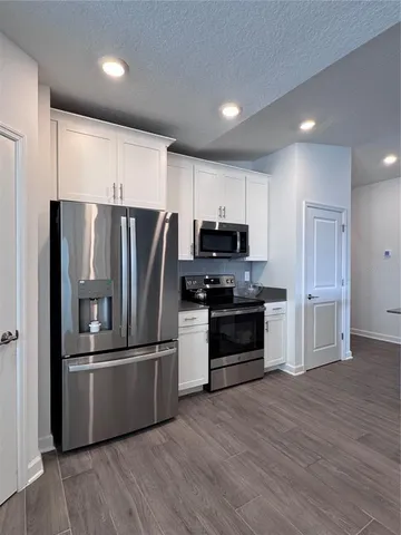 a kitchen with granite countertop a refrigerator cabinets and wooden floor