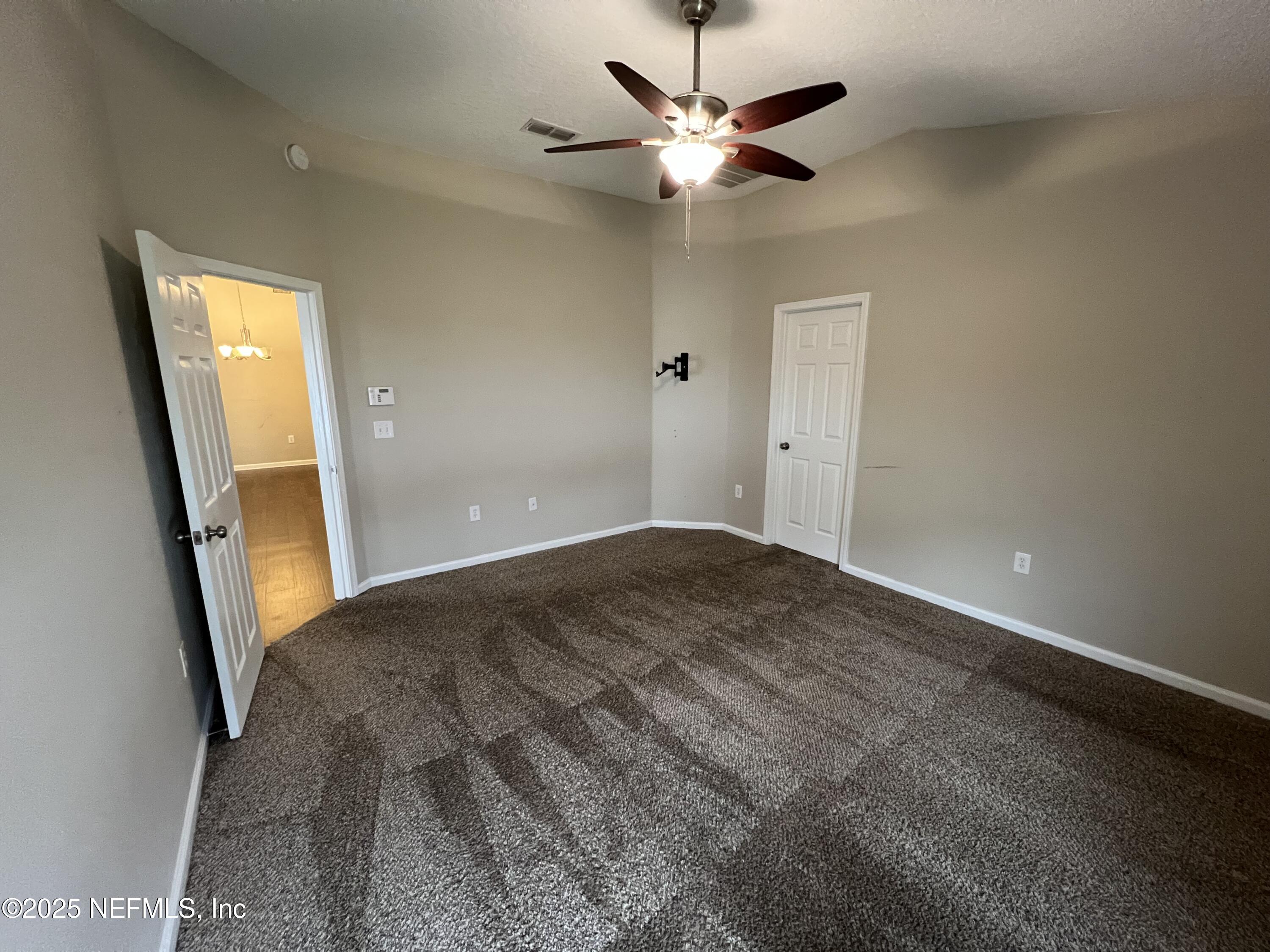1960 McGirts Point Boulevard Jacksonville, FL 32221 - Photo 11 of 18 an empty room with a chandelier fan and windows