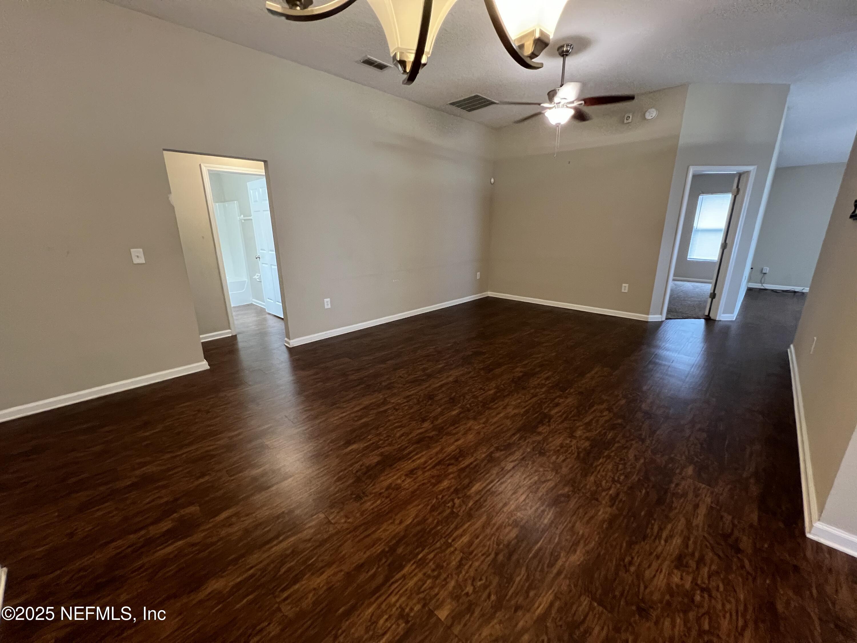 1960 McGirts Point Boulevard Jacksonville, FL 32221 - Photo 5 of 18 a view of an empty room with wooden floor and a chandelier fan