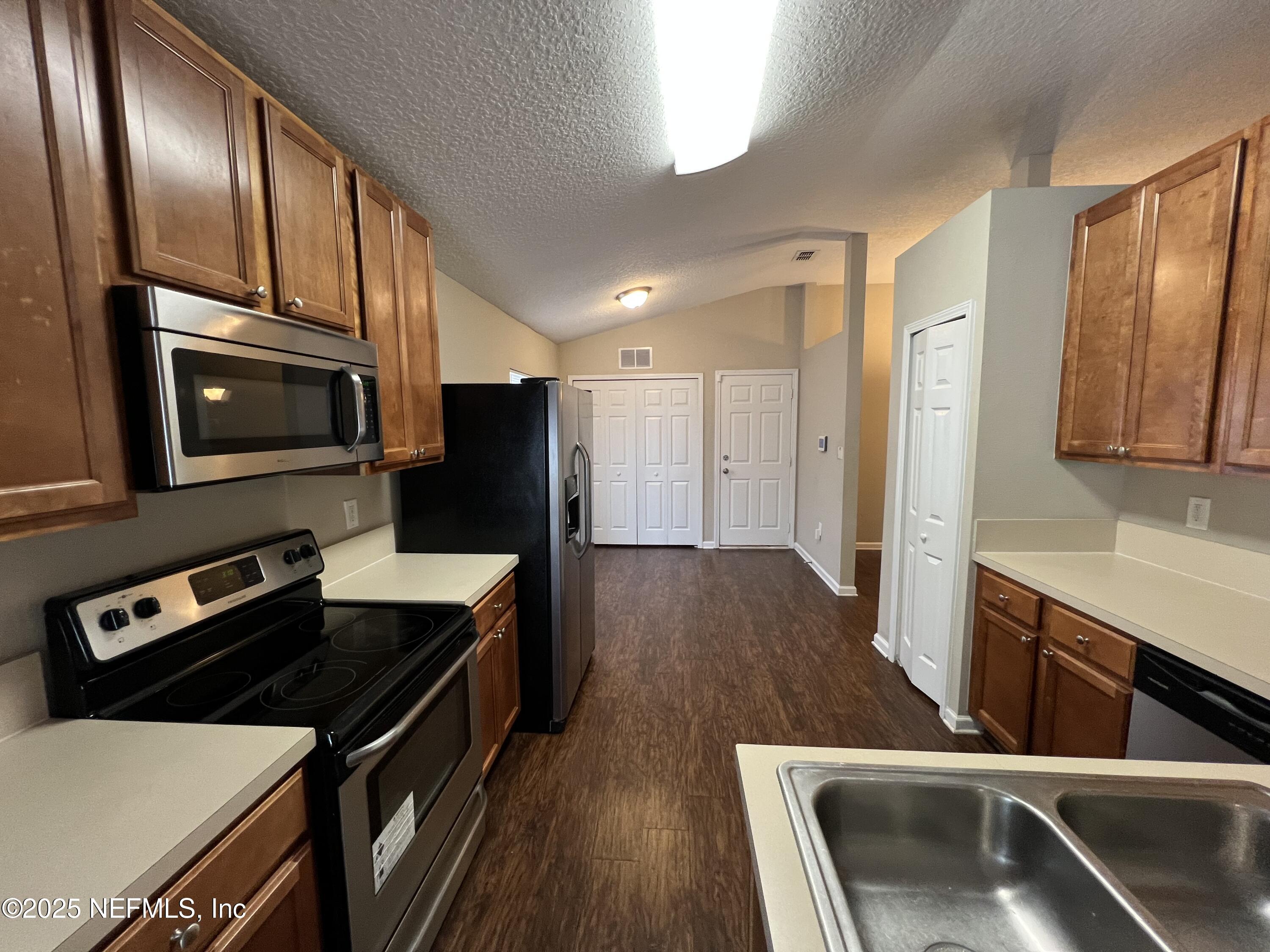 1960 McGirts Point Boulevard Jacksonville, FL 32221 - Photo 7 of 18 a kitchen with stainless steel appliances a stove a sink a microwave and wooden cabinets