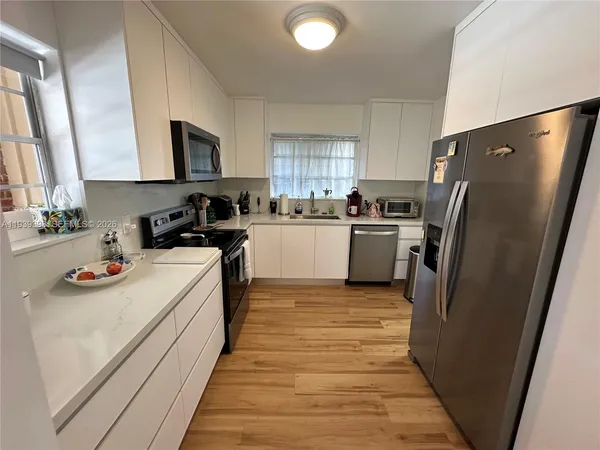 a kitchen with stainless steel appliances a refrigerator a sink a stove a microwave and wooden floors