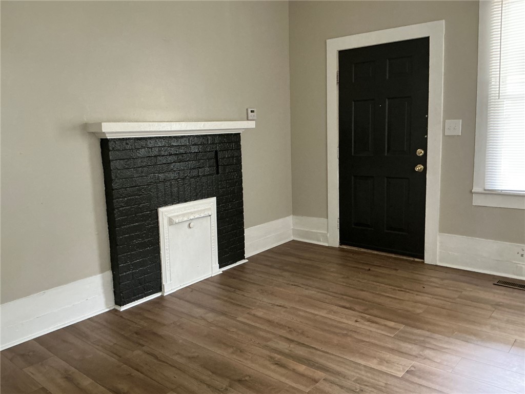 504 Caughlin Avenue Anderson, SC 29624 - Photo 3 of 15 A dark brick fireplace feature complements the warm flooring, providing a welcoming atmosphere.