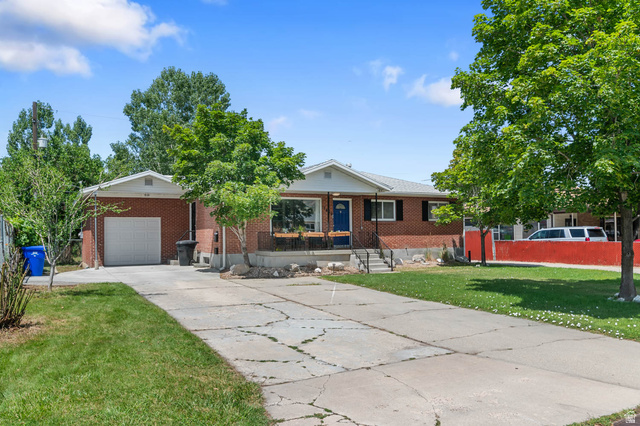 1489 North 400 West Bountiful, UT 84010 - Photo 2 of 47 Brick exterior residence with an attached garage, a paved driveway, and mature landscaping