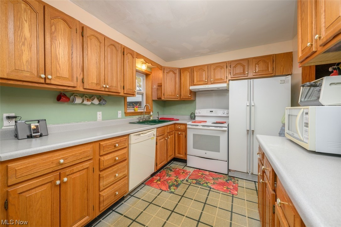 241 Everhard Road Southwest North Canton, OH 44709 - Photo 5 of 21 Kitchen with updated cabinets, spacious countertops and vinyl flooring. Dishwasher, Side by Side Fridge and oven with range hood