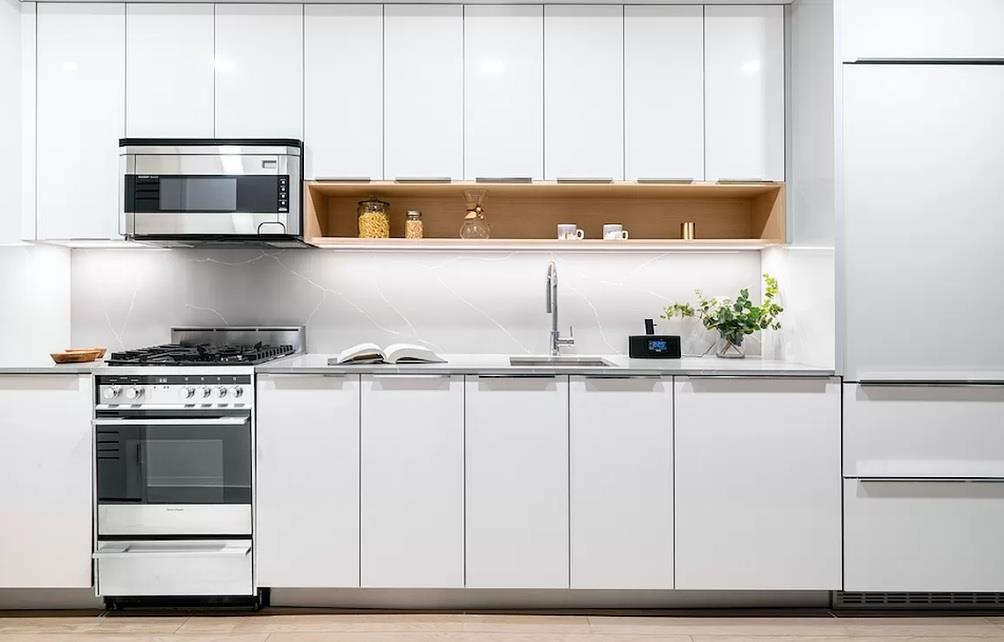 20 Broad Street, Unit 1513 Manhattan, NY 10005 - Photo 2 of 3 a kitchen with stainless steel appliances a stove a microwave and cabinets