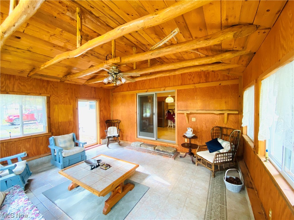 19119 West Middletown Road Beloit, OH 44609 - Photo 18 of 28 Tiled living room with ceiling fan, wooden walls, lofted ceiling with beams, and wooden ceiling