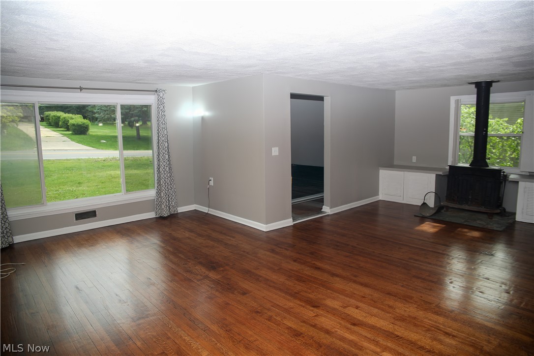 1087 Krumroy Road Akron, OH 44306 - Photo 4 of 23 Spacious living area featuring wood-finish flooring, a large picture window, and a built-in wood-burning stove with stone hearth
