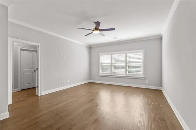an empty room with wooden floor ceiling fan and windows