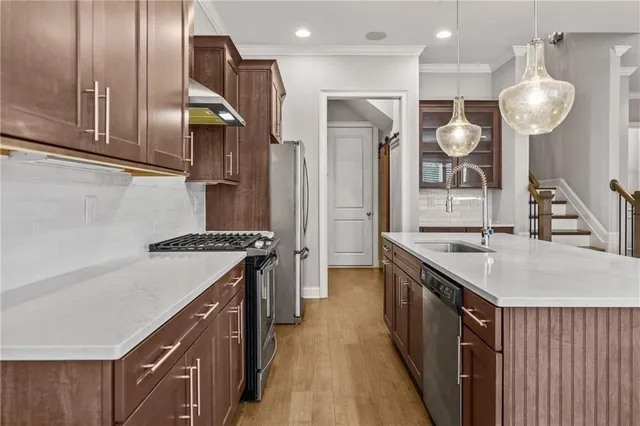 a kitchen with stainless steel appliances granite countertop a sink a stove and a refrigerator