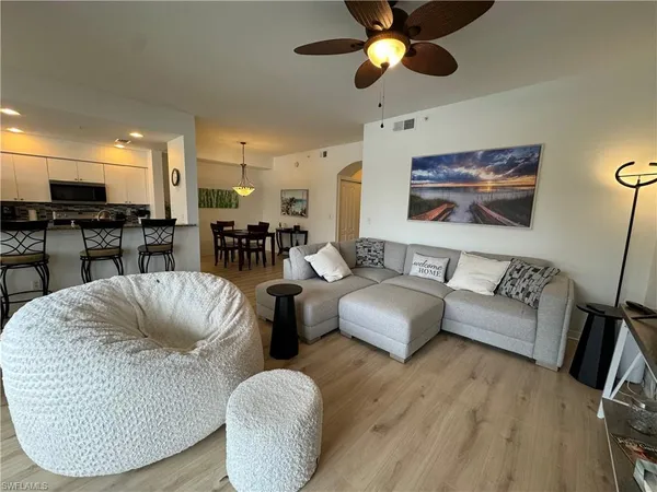 a living room with furniture kitchen view and a large window