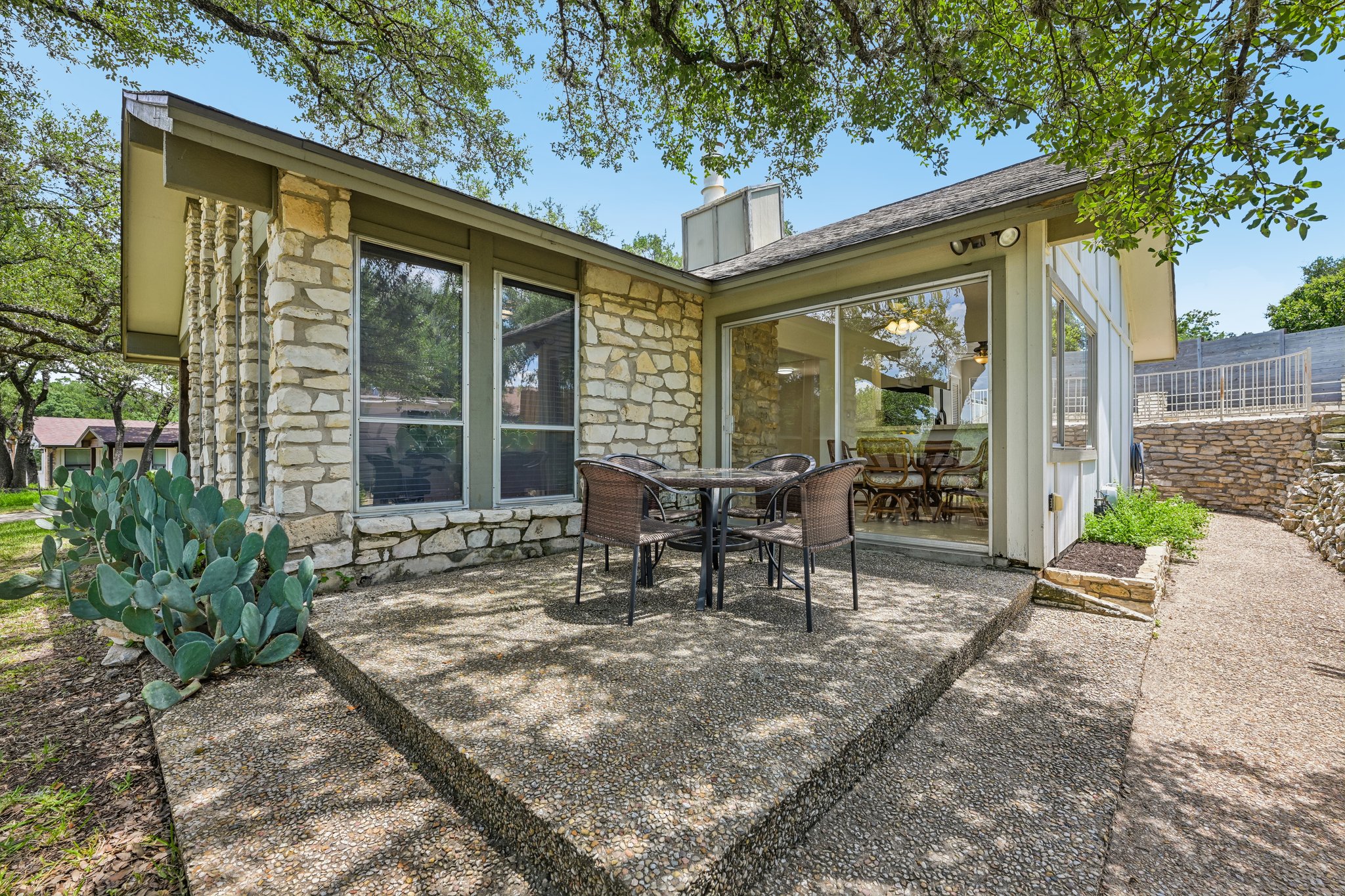 13101 Travis View Loop Austin, TX 78732 - Photo 19 of 27 A private stone patio and glass-enclosed dining area create a serene outdoor living space.