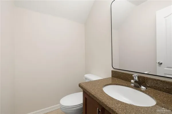 a bathroom with a granite countertop toilet sink and mirror