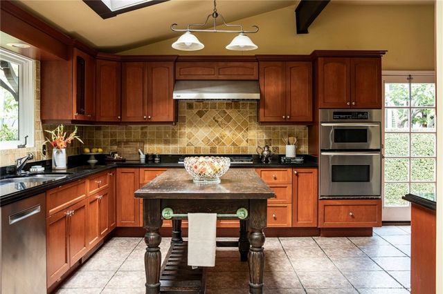a kitchen with stainless steel appliances granite countertop wooden cabinets a stove top oven a sink and dishwasher