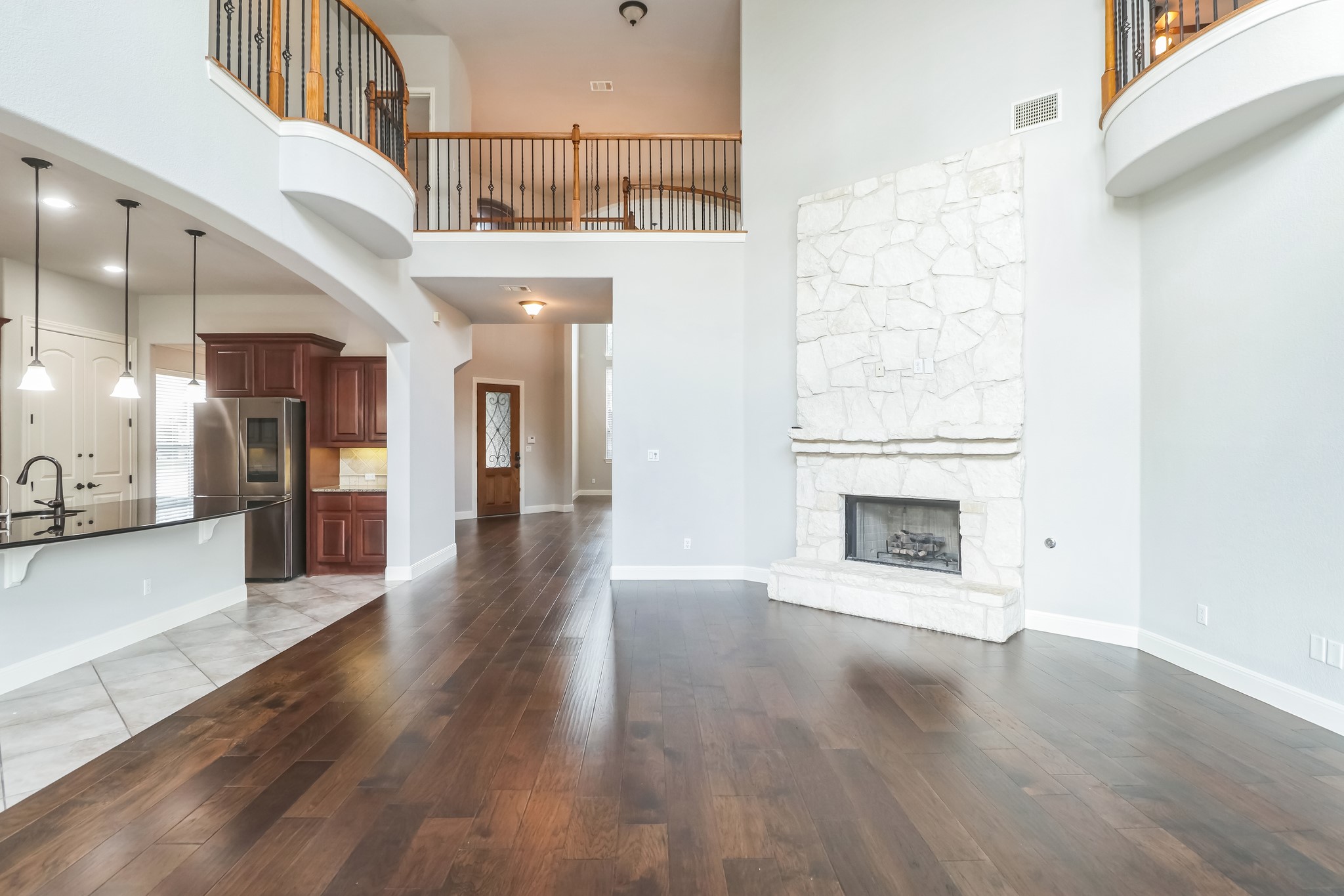 Soaring ceilings and a floor-to-ceiling stone fireplace anchor this light-filled living space.