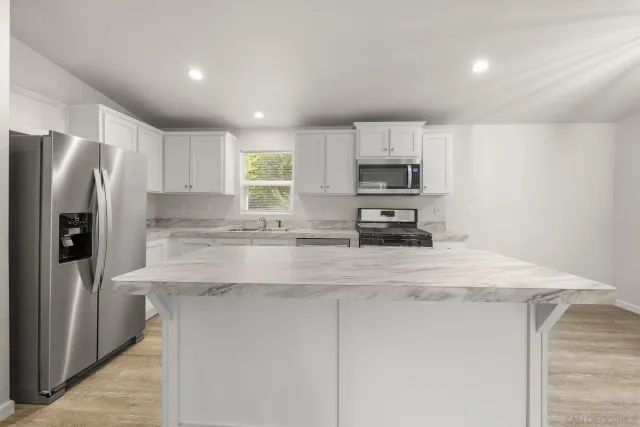 a kitchen with stainless steel appliances granite countertop a sink stove and microwave