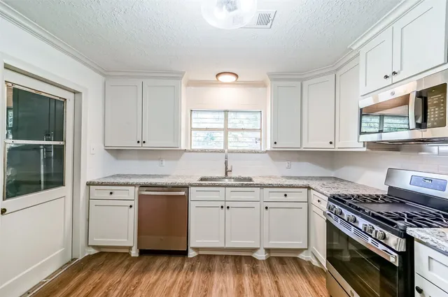a kitchen with a stove a sink and wooden floor