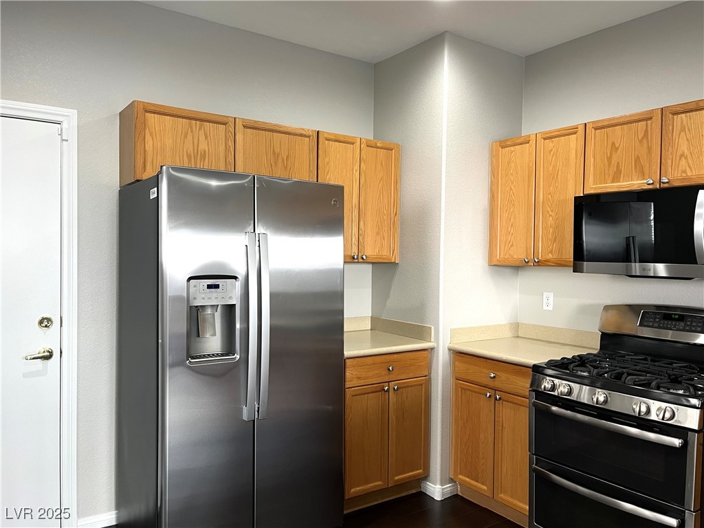 231 Spectacular Street Henderson, NV 89052 - Photo 8 of 66 Kitchen with breakfast nook/bar, oak cabinets, wood laminate flooring, corian countertops, recesses lighting, SS appliances and pantry