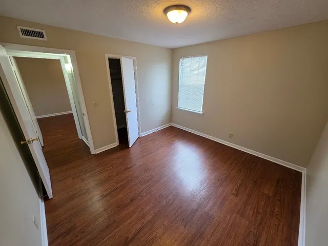 an empty room with wooden floor and windows