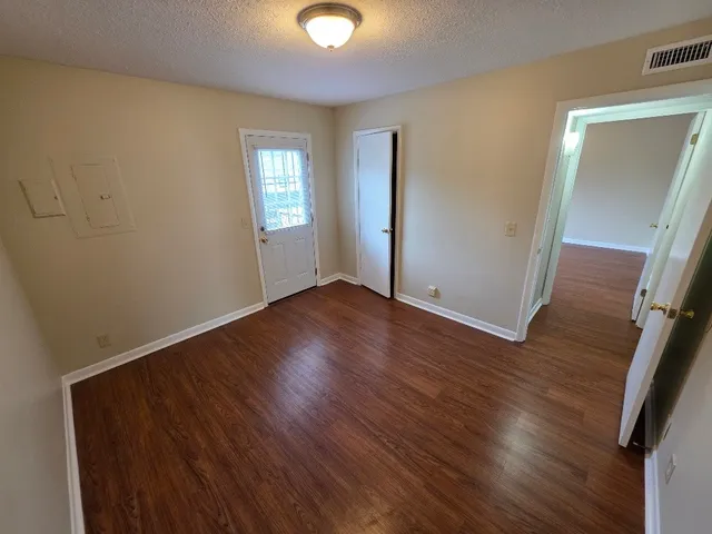 an empty room with wooden floor and windows