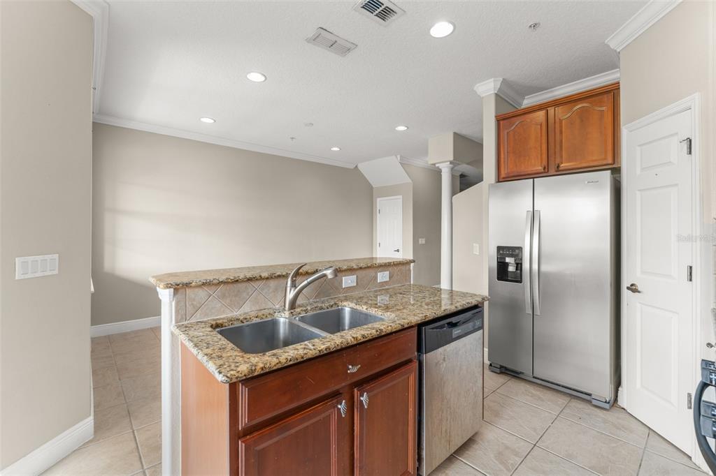 868 Assembly Court Reunion, FL 34747 - Photo 12 of 43 a kitchen with granite countertop kitchen island stainless steel appliances a sink a refrigerator and a cabinets