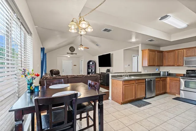 a kitchen with stainless steel appliances granite countertop a stove a sink dishwasher a dining table and chairs with wooden floor