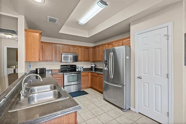 a kitchen with granite countertop a refrigerator stove and sink