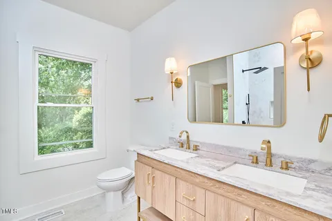 a bathroom with a granite countertop sink toilet and mirror