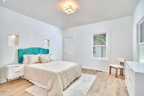 a bedroom with a bed and a table lamp on dresser
