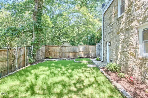 a view of a backyard with large trees and wooden fence