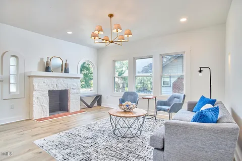 a living room with furniture a chandelier and a fireplace