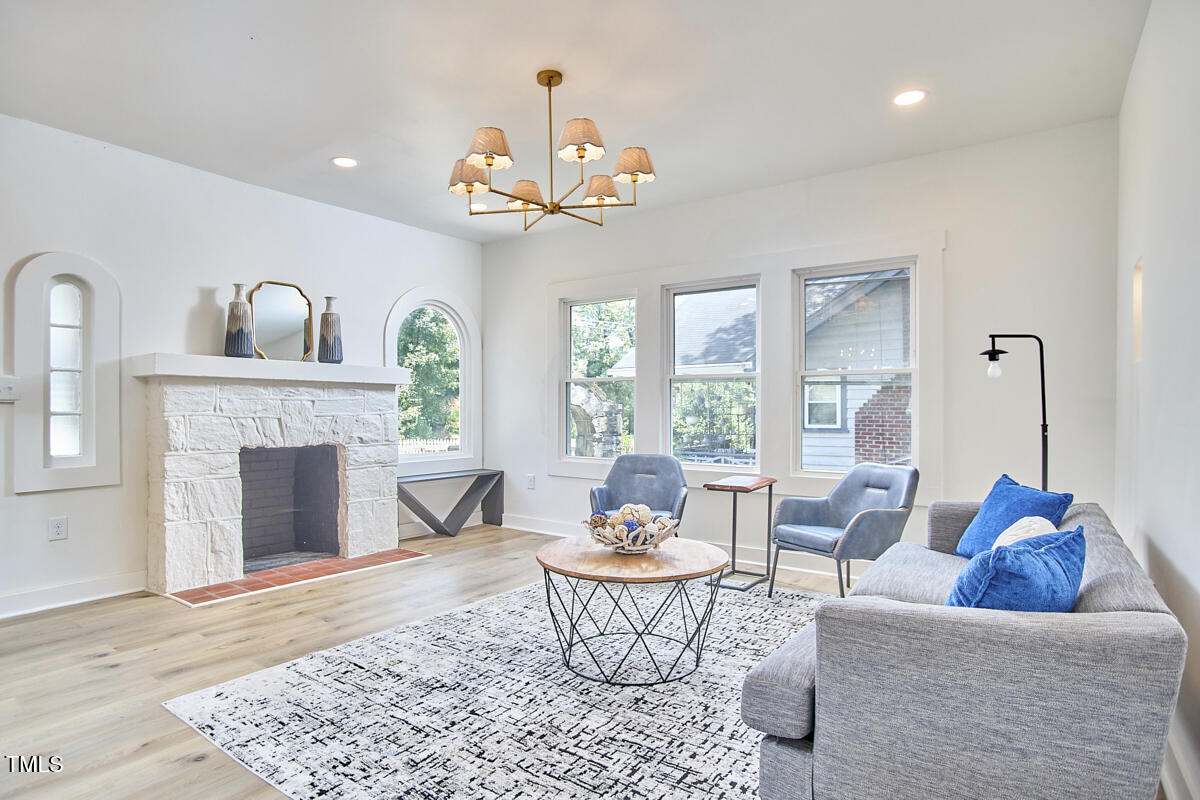 2203 University Drive Durham, NC 27707 - Photo 5 of 40 a living room with furniture a chandelier and a fireplace