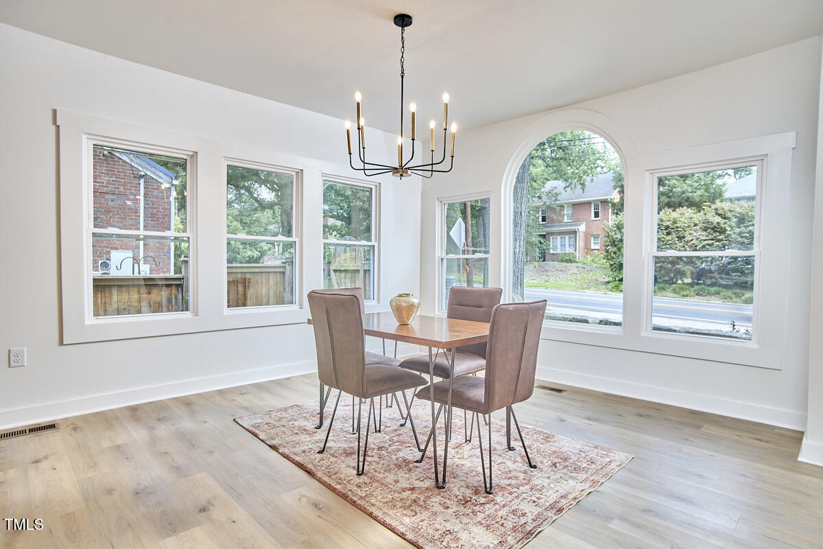 2203 University Drive Durham, NC 27707 - Photo 7 of 40 a dining room with wooden floor a chandelier a wooden table and chairs