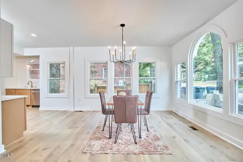 a dining room with wooden floor a chandelier a wooden table and chairs
