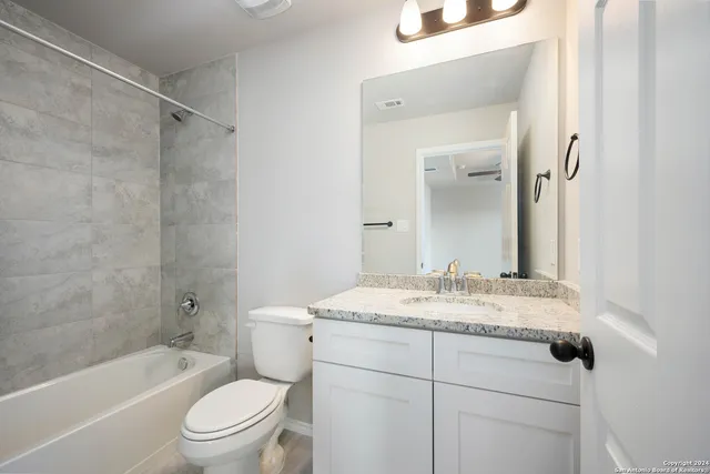 a bathroom with a granite countertop sink toilet vanity mirror and bathtub
