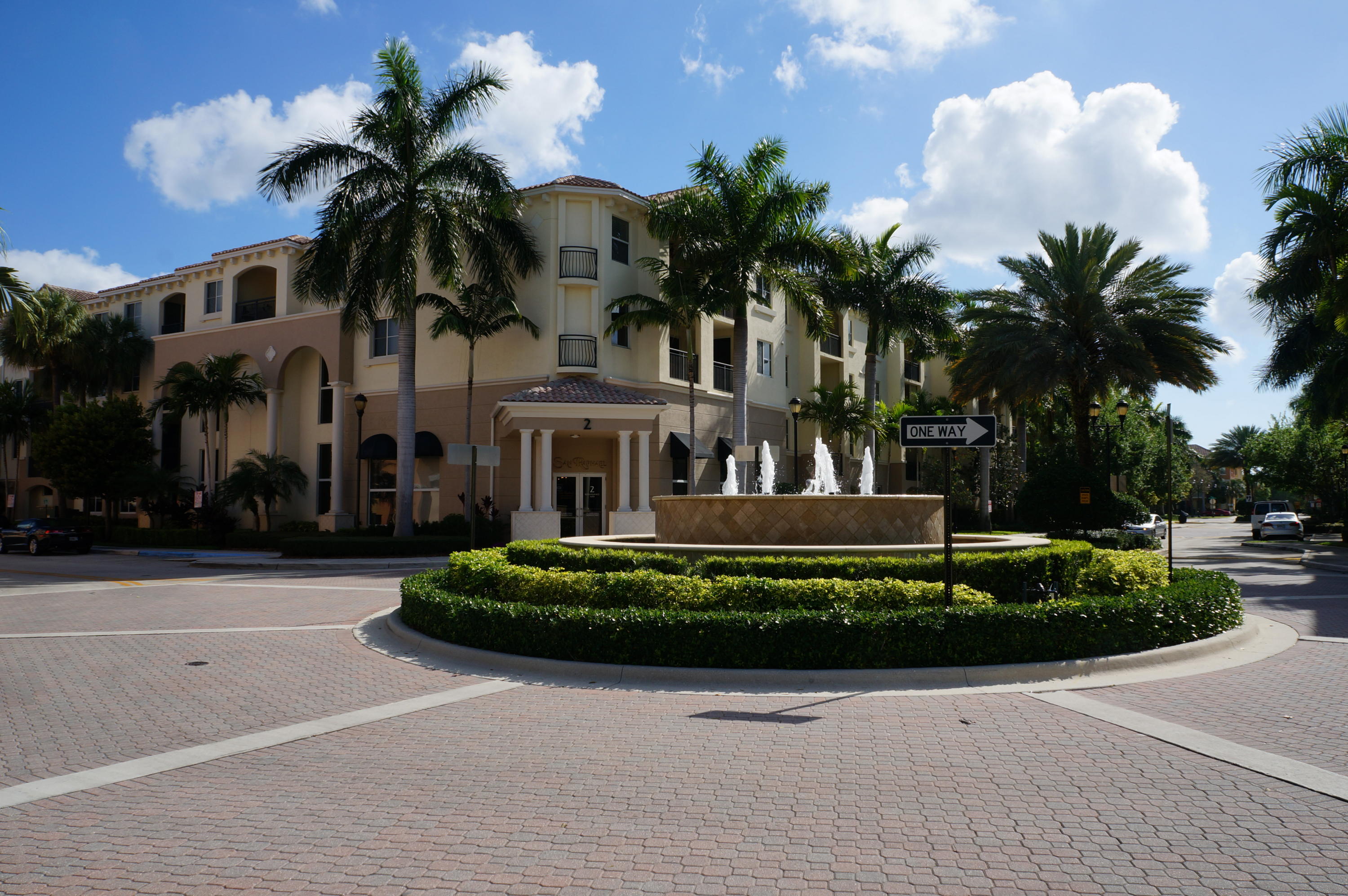 a front view of a house with a garden and palm trees