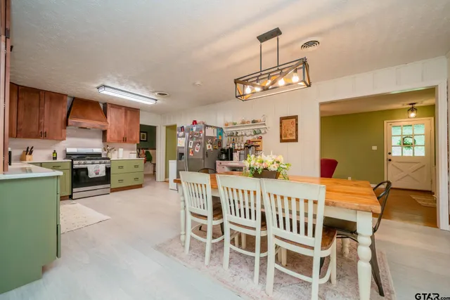 a view of a dining room with furniture a kitchen and chandelier