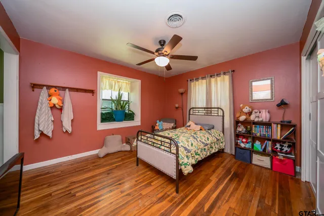 a bedroom with a bed and a bookshelf with wooden floor