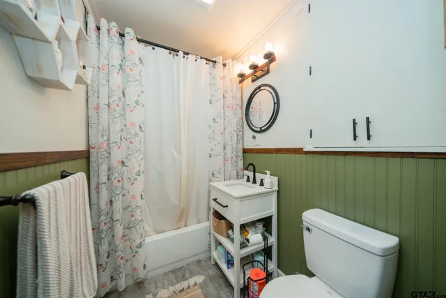 a bathroom with a toilet sink and shower curtain