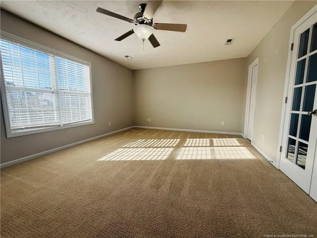 an empty room with windows and fan