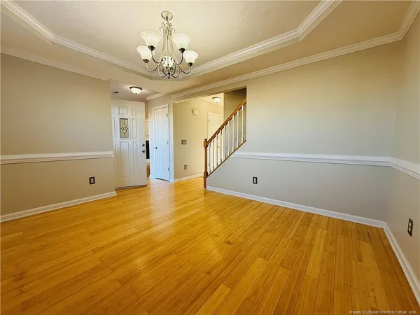 a view of an empty room with wooden floor and a ceiling fan