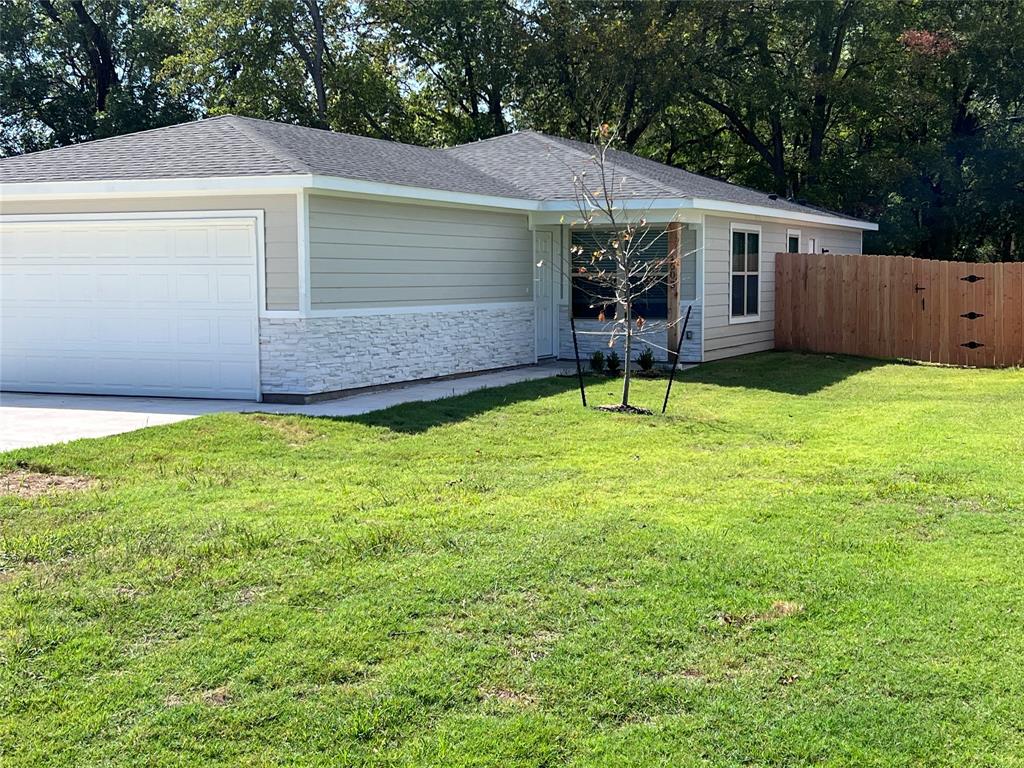 Ranch-style home featuring stone siding, an attached garage, roof with shingles, driveway, and a gate