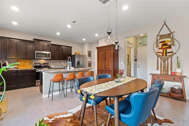 a kitchen with stainless steel appliances kitchen island granite countertop a dining table chairs refrigerator and microwave