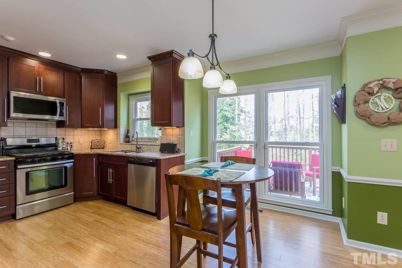 4305 Birmingham Way Raleigh, NC 27604 - Photo 4 of 23 a kitchen with stainless steel appliances granite countertop a stove top oven a sink dishwasher a dining table and chairs with wooden floor