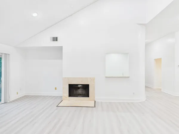 an empty room with wooden floor and a fireplace