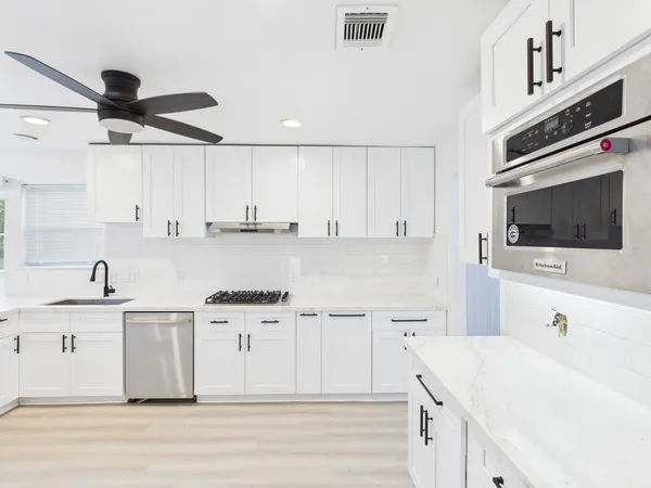 a kitchen with stainless steel appliances kitchen island granite countertop a sink a stove and cabinets