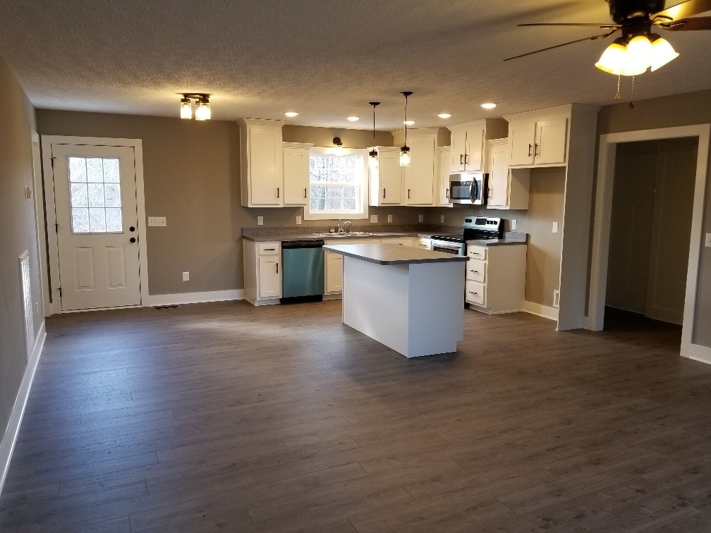 210 Hog Back Ridge Road Bethpage, TN 37022 - Photo 6 of 13 a open kitchen with kitchen island a sink dishwasher a refrigerator and a fireplace with wooden floor
